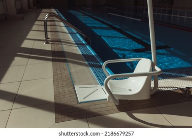 Chair Lift For Disabled People Installed At Poolside In Swimming Pool On Sunny Day 