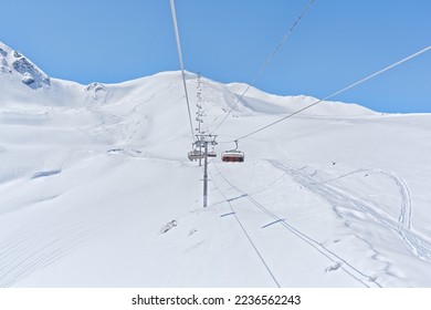 Chair lift going to the top of the mountain of the southern slope of Arkhyz. A beautiful view on a clear day of the snow-white peaks of the mountains.