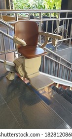 The Chair Moves Up The Electric Staircase, For The Disabled And The Elderly With Straight Rail On The Stair Background.