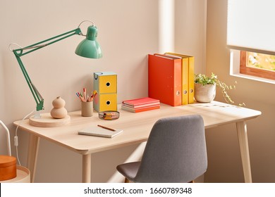 Chair placed near table with lamp and colorful stationery in cozy home office in morning - Powered by Shutterstock