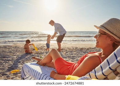 Chair, relax or children with woman at beach on holiday vacation or weekend together with dad or family. Father, calm mother or kids siblings at sea for bonding or break in nature in Spain in summer - Powered by Shutterstock