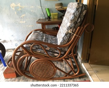 A Chair For Relaxing Made Of Rattan, In Front Of The Terrace Of A House, With Foam Cushions As A Seat And Backrest