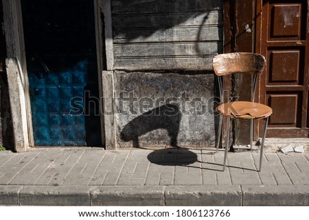 a chair and its shadow on a wall and pavement