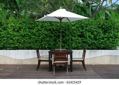 Chair, Table And White Umbrella In Garden