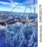 A chairlift on a mountain in Vermont with snow covered trees and the Mad River Valley in the background