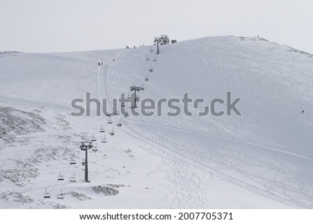 The chairlift stretches to the top of the ski resort. The mountainside is covered with traces of skis and snowboards. The concept of active recreation
