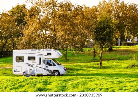 Chairs in front of motorhome. Camping on autumn nature. Holidays and travel with recreational vehicle..