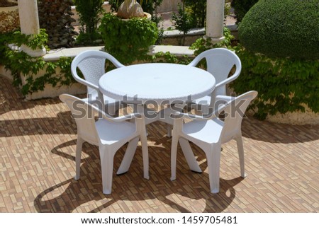 chairs with a plastic table in a garden 