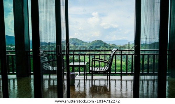 Chairs for relaxation and watching the mountains.,\
Overlooking the window of a balcony with transparent curtains and\
nice view over the mountain.,Beautiful terrace view over the\
mountain., copy space
