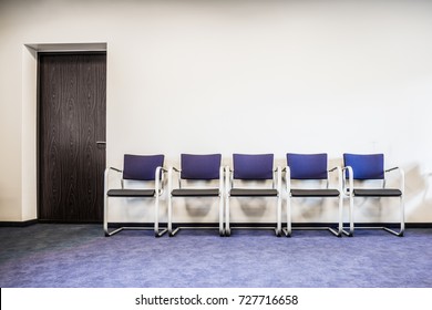 Chairs Row On The Blue Carpet Floor At The Door. Waiting Room In Office, Hospital, Clinic, Education Or Other Institution. Place For Waiting In Line Of Job Interview And Casting. Interior Concept.