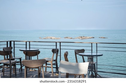 Chairs and Tables by   the wood fence at the beach. The cafe outdoor seats.  Coffee shop by the ocean. Thailand beach scenery . - Powered by Shutterstock