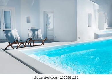 Chaise lounges near the swimming pool. White architecture in Santorini island, Greece. Travel and vacation concept - Powered by Shutterstock