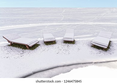 Chaise Lounges Under The Snow. Snow Covered Beach. Unexpected Weather Change.