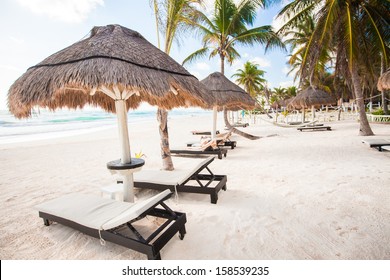 Chaise lounges under an umbrella on sandy beach