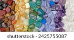 Chakra Crystal Healing wide Background template - Rows of tumbled polished healing crystal laid out in chakra colours white, purple, blue, green, yellow, orange, red ideal for crystal healing theme
