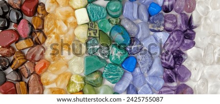 Chakra Crystal Healing wide Background template - Rows of tumbled polished healing crystal laid out in chakra colours white, purple, blue, green, yellow, orange, red ideal for crystal healing theme
