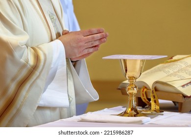 Chalice On The Altar And Priest Celebrating Mass In The Background And Empty Space For Text