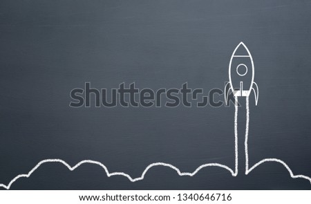 chalk drawing rocket on blackboard Going up quickly