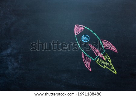 Chalk space rocket painted on school chalkboard.