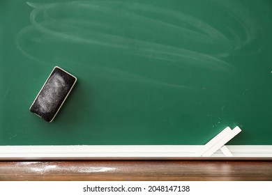Chalk with sponge and blackboard in classroom