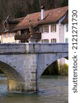 Chalk stone bridge over the river Doubs at little medieval town St-Ursanne, Canton Jura, on a sunny winter morning. Photo taken February 7th, 2022, Saint-Ursanne, Switzerland.