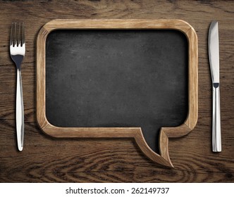 chalkboard with fork and knife on wooden dinning table - Powered by Shutterstock