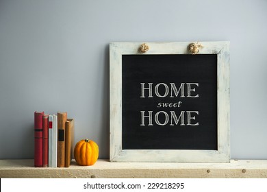 chalkboard frame on the grey wall with books and pumpkin HOME SWEET HOME