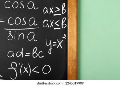 Chalkboard with many different math formulas on green wall, closeup