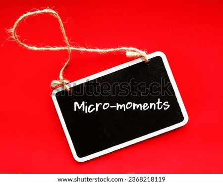 Chalkboard on red background with buzzword MICRO- MOMENTS, small moments of consumers before making a purchase decision - short precious times when brands get to interact with consumer