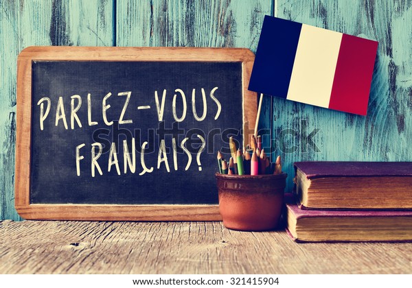 a chalkboard with the question\
parlez-vous francais? do you speak french? written in french, a pot\
with pencils and the flag of France, on a wooden\
desk
