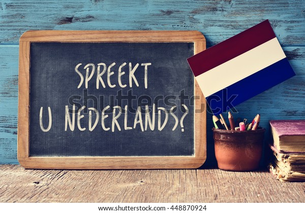 a chalkboard\
with the question Spreekt u Nederlands?, do you speak Dutch?\
written in Dutch, a pot with pencils, some books and the flag of\
the Netherlands on a wooden\
desk