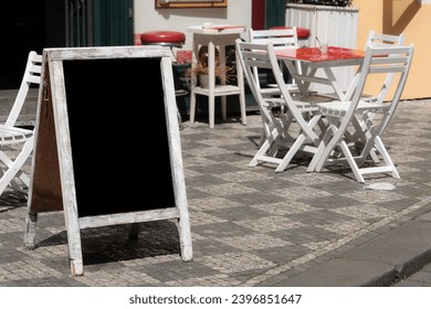 chalkboard, side view empty or blank restaurant menu blackboard on street over chair and tables of a cafe. black menu chalkboard mockup, menu board template. cafe or restaurant concept background