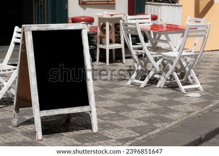 chalkboard, side view empty or blank restaurant menu blackboard on street over chair and tables of a cafe. black menu chalkboard mockup, menu board template. cafe or restaurant concept background