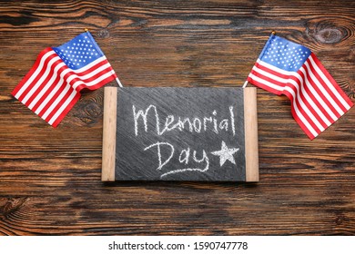 Chalkboard with text MEMORIAL DAY and USA flags on wooden background - Shutterstock ID 1590747778