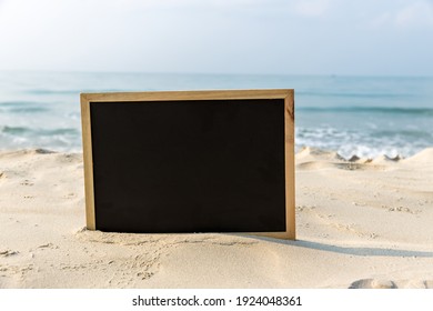 Chalkboard with a wooden frame Blank Chalk board for write text, message or advertising, placed on the sand of a beach. Empty blackboard on sandy beach. - Powered by Shutterstock