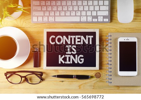 Chalkboard written CONTENT IS KING on wooden desk with flare effect                  