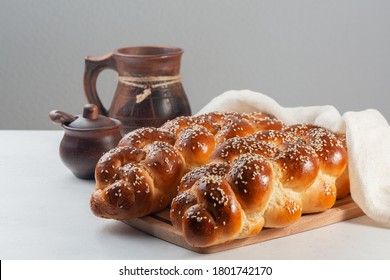 Challah bread with poppy and sesame seeds. Covered with white cover. On white and grey background.