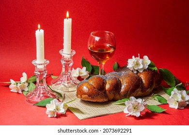 Challah bread, shabbat wine and candles on red background. Lighting a candle. Shabbat Shalom