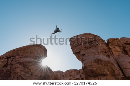 Challenge, risk and freedom concept. Silhouette a man jumping over precipice crossing cliff