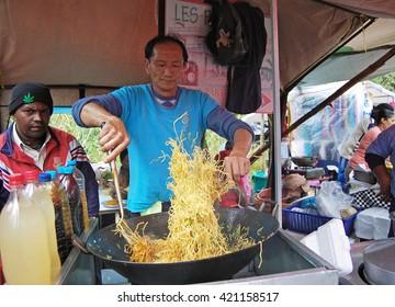 Chamarel, Mauritius. August 2010. Mauritian Asian Man Skillfully Flipping Noodles In A Wok At A Food Tent During The Village Fair.