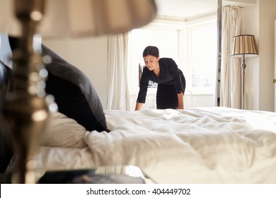 Chambermaid Changing Bed Linen On The Bed In A Hotel Room