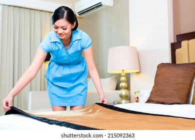 Chambermaid Making Bed In Asian Hotel Room