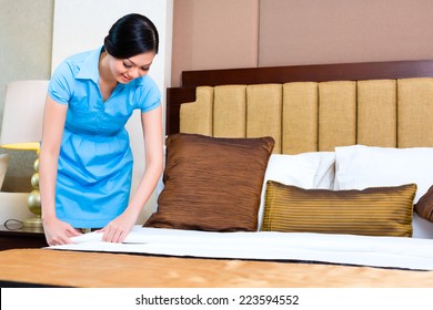 Chambermaid Making Bed In Asian Hotel Room