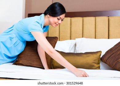 Chambermaid Making Bed In Asian Hotel Room