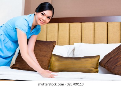 Chambermaid Making Bed In Asian Hotel Room