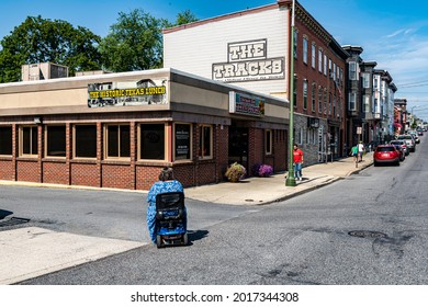 Chambersburg Pennsylvania USA 7-16-2021 Handicap Woman In Motorized Wheelchair Crossing Street To Restaurant