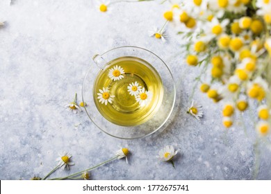 Chamomile flowers and chamomile tea in glass teacup, top view, prevention of seasona flu colds