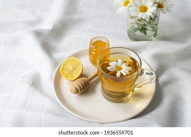 Chamomile flowers and chamomile tea. Chamomile tea in glass teacup with flowers, honey and lemon, top view, prevention of seasona flu colds