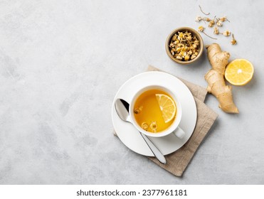 Chamomile herbal tea with lemon in a white cup on a light background with dry flowers and ginger. The concept of a healthy detox drink for health and immunity. Top view and copy space. - Powered by Shutterstock