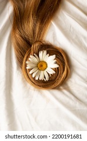 Chamomile in long hair on the background of a white bed - Shutterstock ID 2200191681